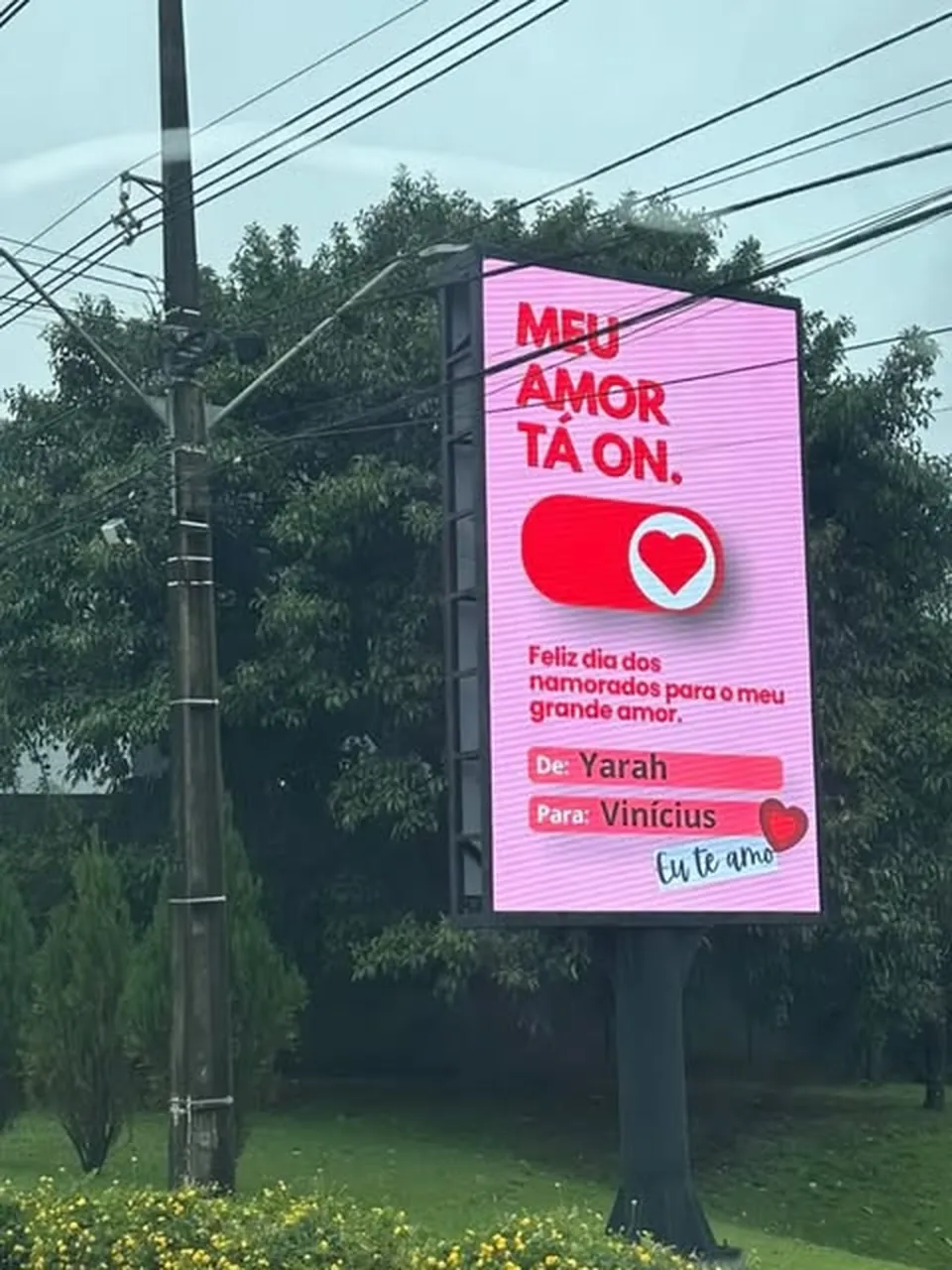 Painel Lumen exibindo mensagem de Dia dos Namorados em avenida arborizada